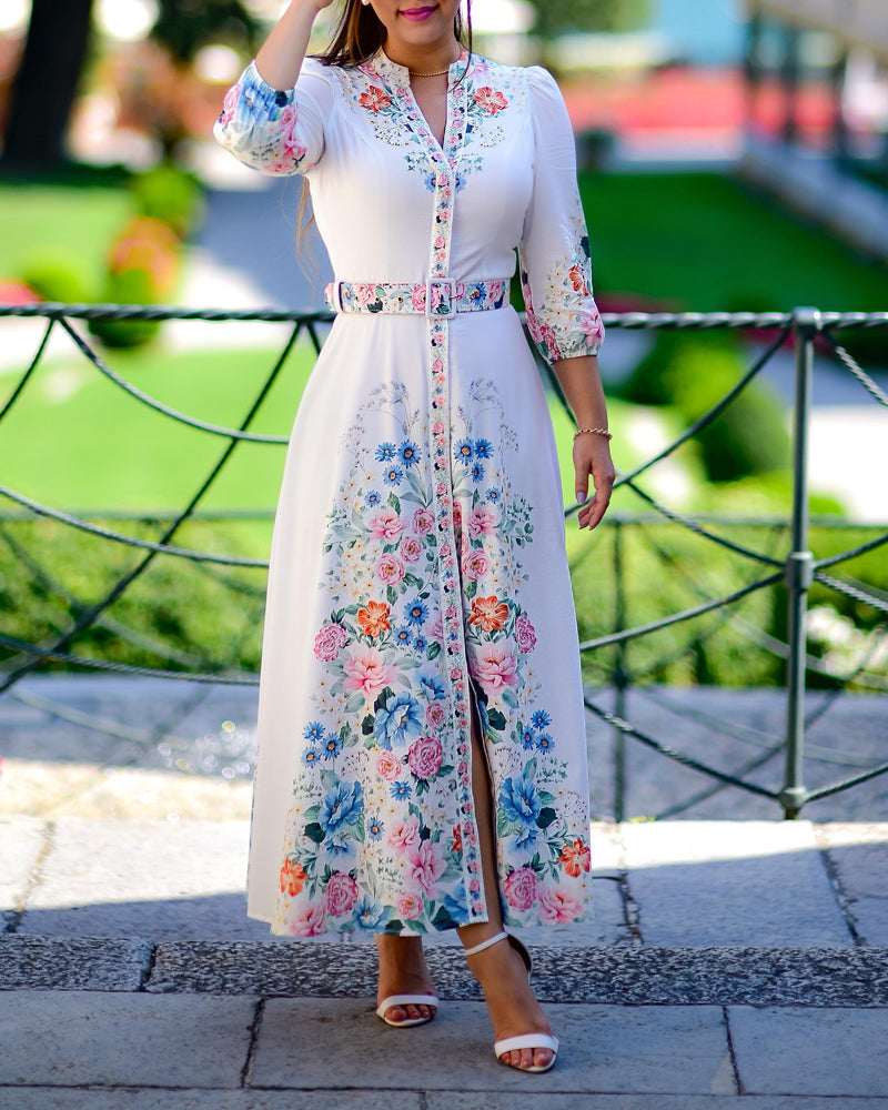 A long white V-neck A-line maxi dress with colorful floral patterns and tie detail sleeves.
