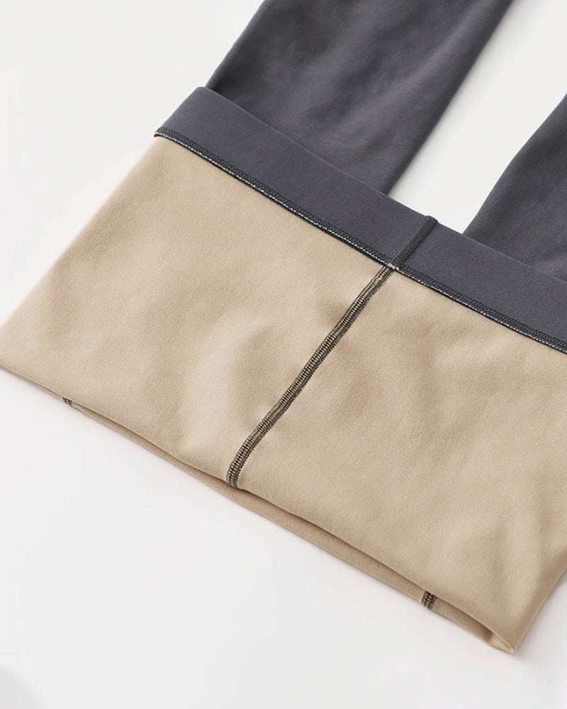 Folded pants in beige and dark gray fabric with visible seam stitching details.