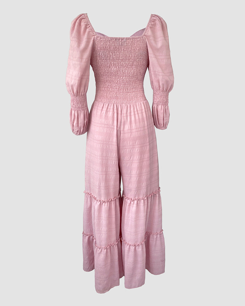 Light pink jumpsuit with sweetheart neck, puff sleeves, shirred ruffle hem, and wide legs.