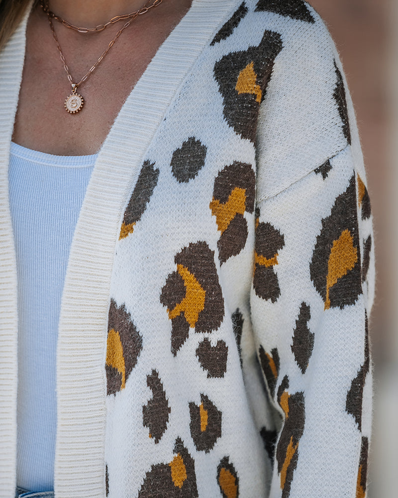 Leopard print longline open-front cardigan layered over a white top and light blue jeans.