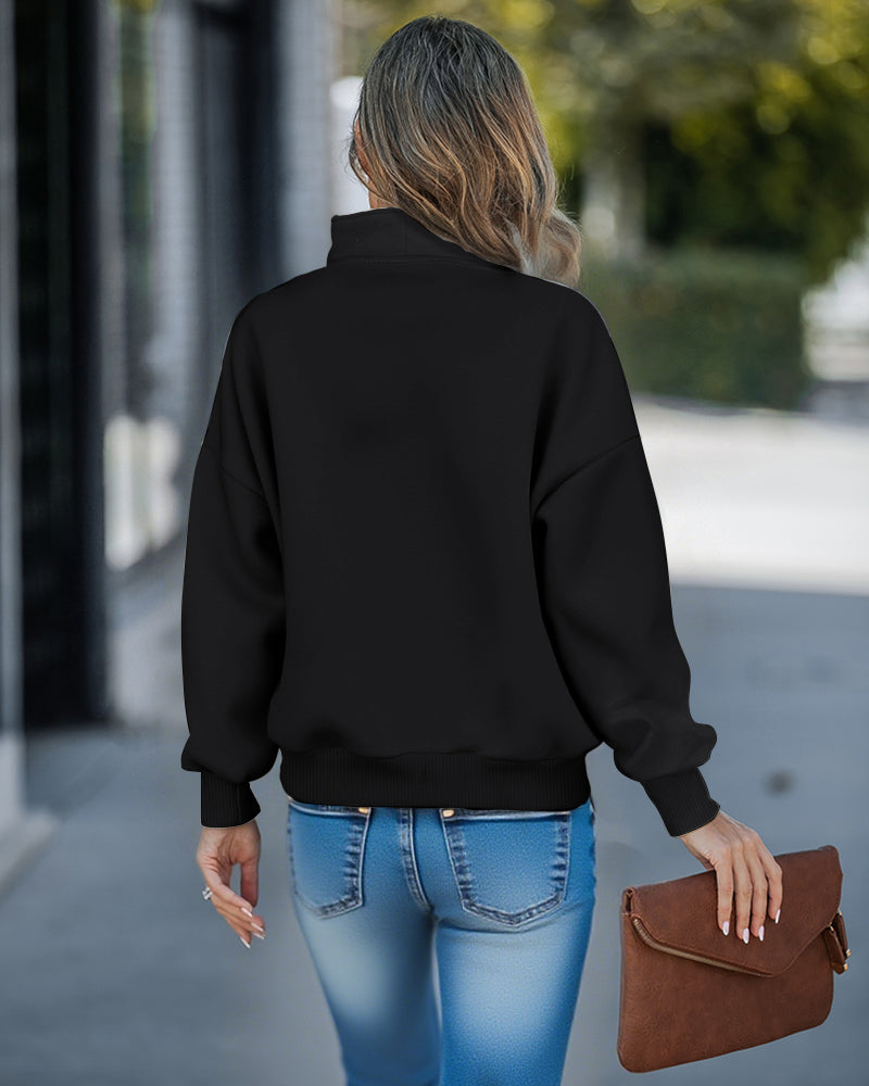 A black high neck half-zip sweatshirt with kangaroo pocket and drop shoulders, blue jeans.