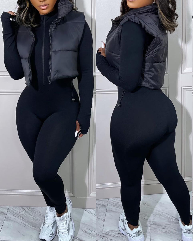 KOAD'CLO stand collar zip-up cropped puffer vest with drawstring hem over black jumpsuit.