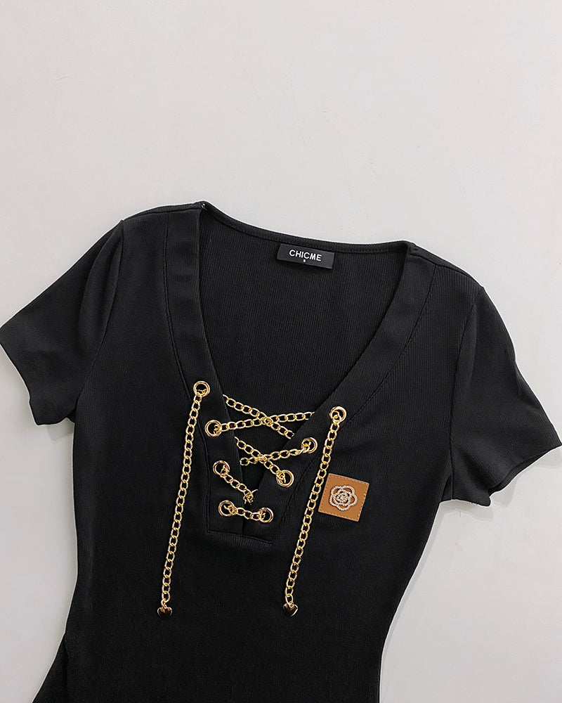 Black short-sleeve V-neck top with gold chain lace-up and rhinestone details.