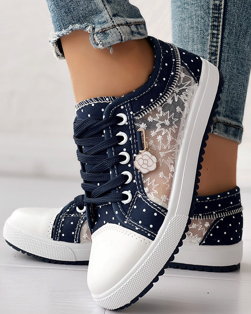 Navy blue sneakers with white polka dots and floral patterns on a light background