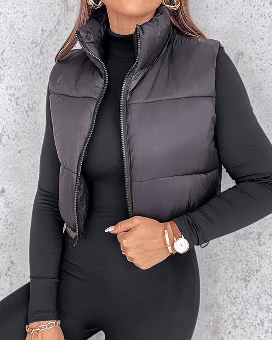 A stand collar zip-up cropped puffer vest with drawstring hem over a long-sleeve black top.