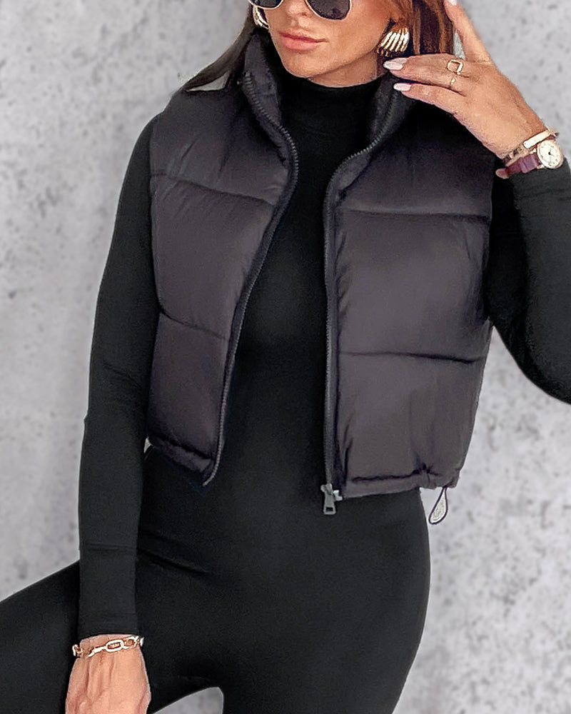 KOAD'CLO stand collar zip-up cropped puffer vest over fitted black top and leggings.