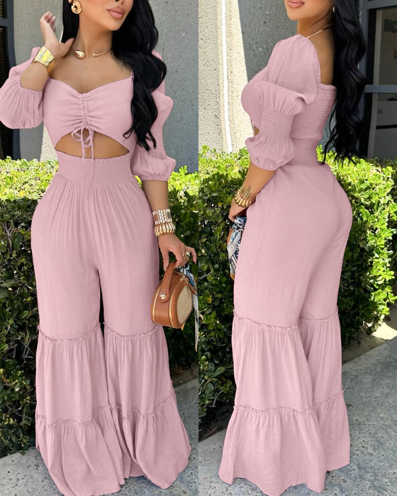 Light pink jumpsuit with sweetheart neck, puff sleeves, shirred bodice, ruffle hem, wide legs.