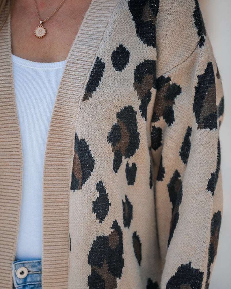 KOAD'CLO  Leopard Print Longline Cardigan with open front over white ribbed top and blue jeans.